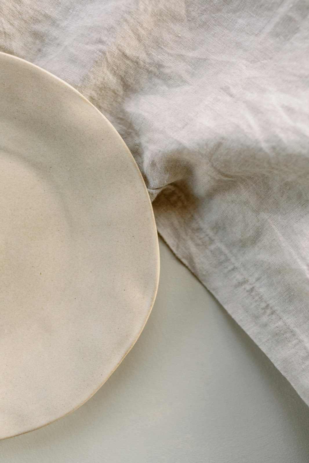 Cream ceramic plate resting on natural linen fabric